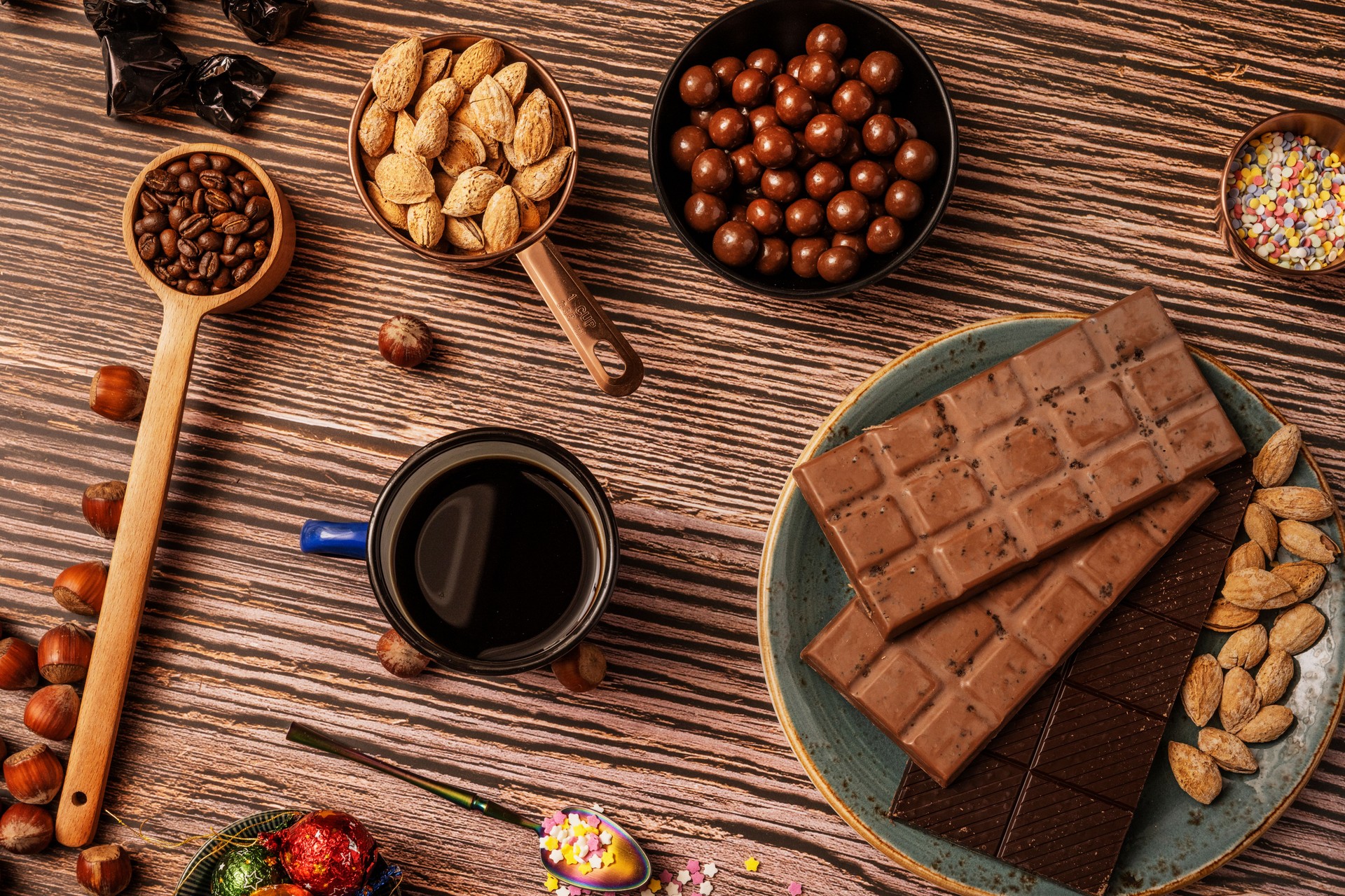 Still life with chocolate in bars with coffee and tea, chocolates, hazelnuts and roasted salted almonds