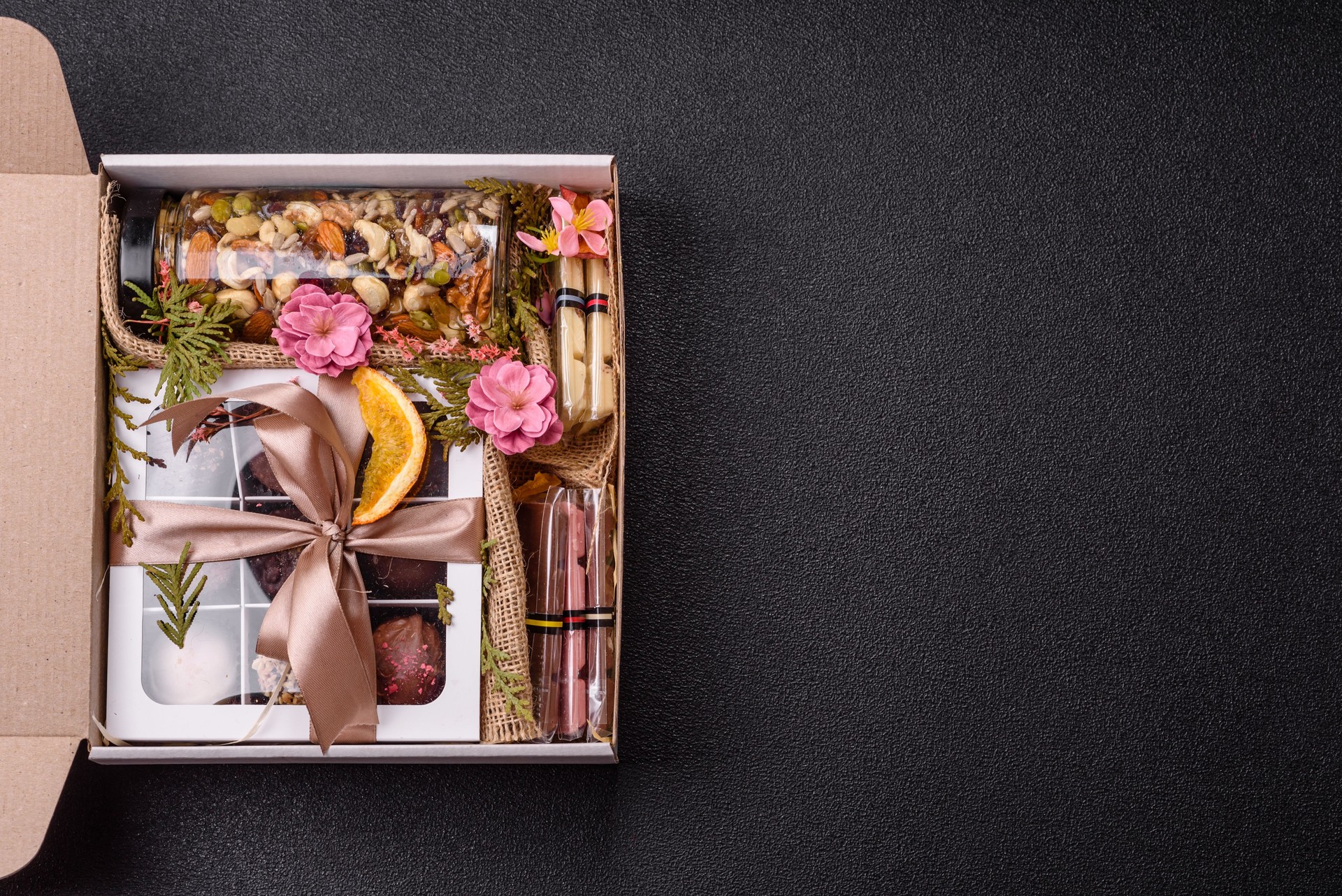 Gift box with a jar of nuts with honey, chocolate and craft candies